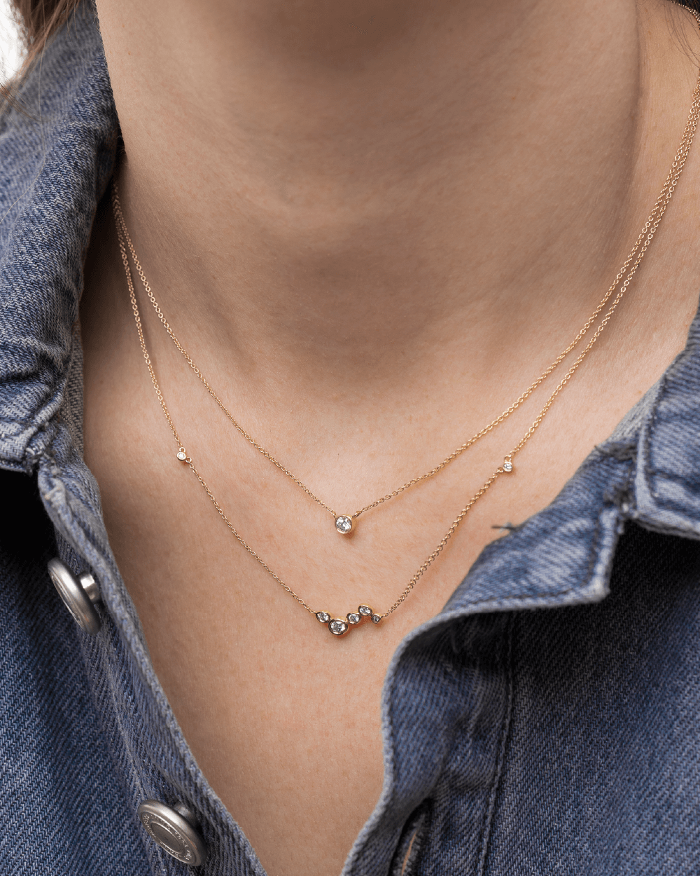 Model med to Eclipse halskæder i 14kt guld med laboratorieskabte diamanter i lag-på-lag.