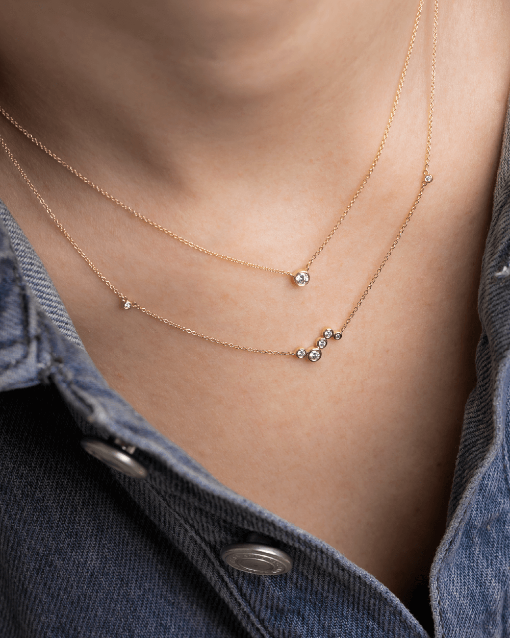 Model med to Eclipse halskæder i 14kt guld med laboratorieskabte diamanter i lag-på-lag.