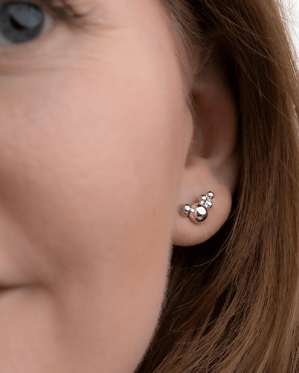 Model med Orbis Cluster ørestik i sterlingsølv med polerede kugledetaljer.