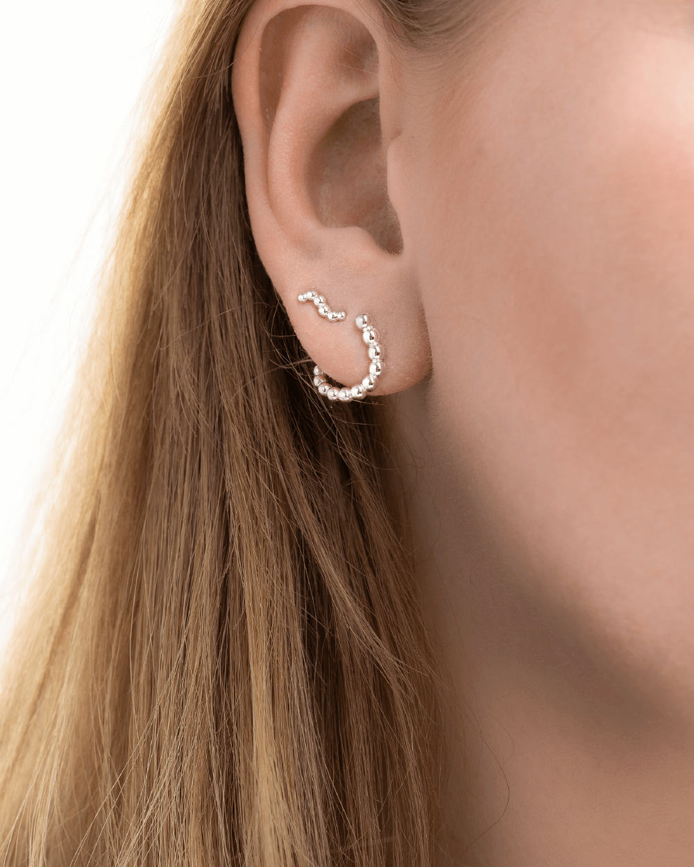 Model med Orbis Drop ørestikker og Orbis Mini ørestikker i sterlingsølv.