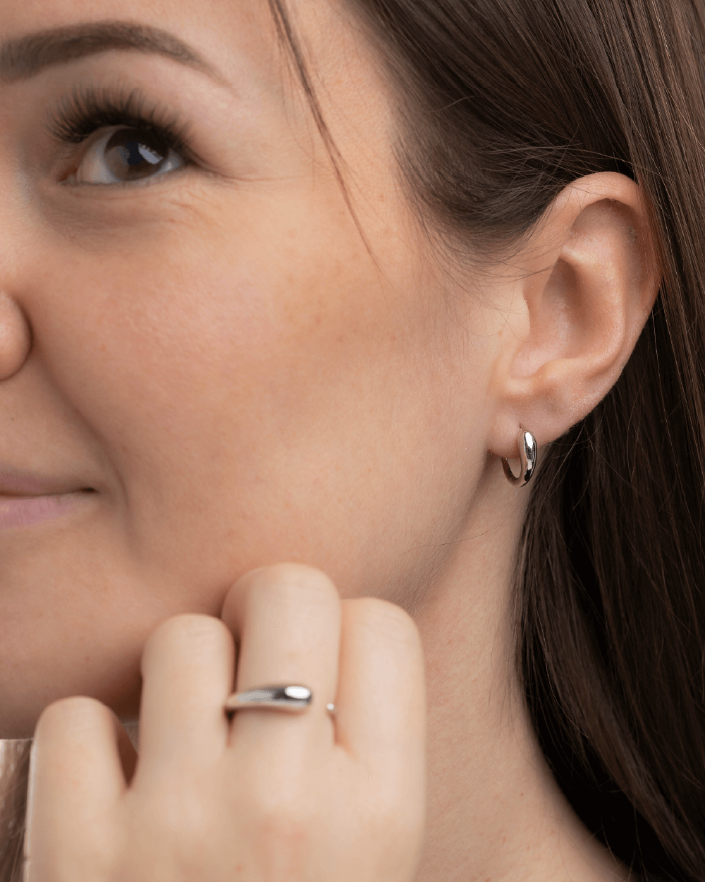 Model med Serene huggies øreringe og Serene ring i sterlingsølv.