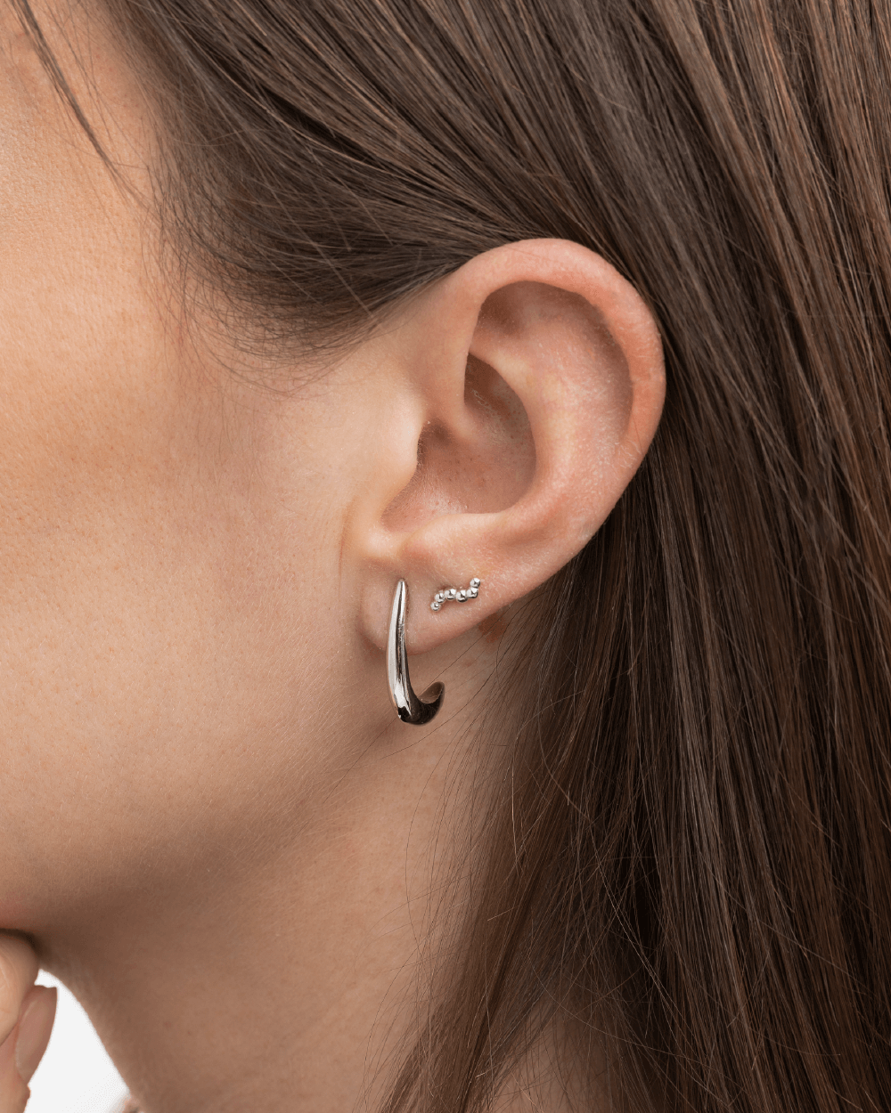 Model med Serene ørering i sterlingsølv kombineret med Orbis mini ørestikker i sterlingsølv.