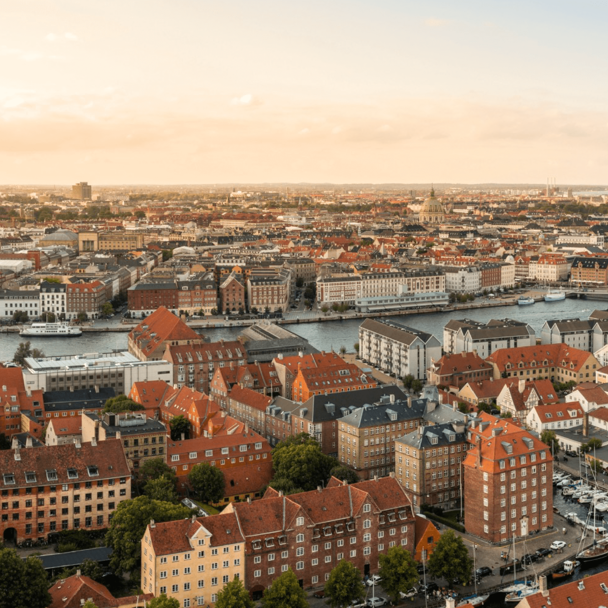 Udsigt over Københavns skyline med havn, tage og kanaler i aftensol.