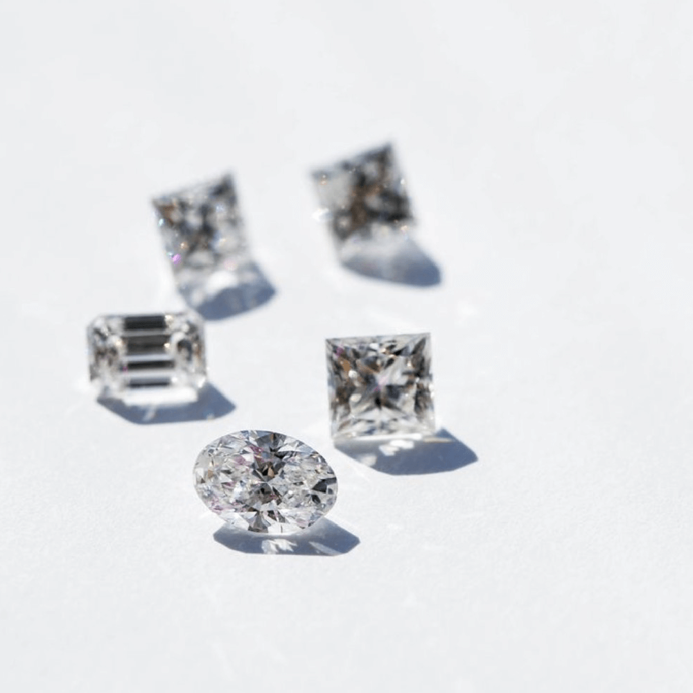 Forskellige diamanter i flere slibformer liggende på en hvid overflade.