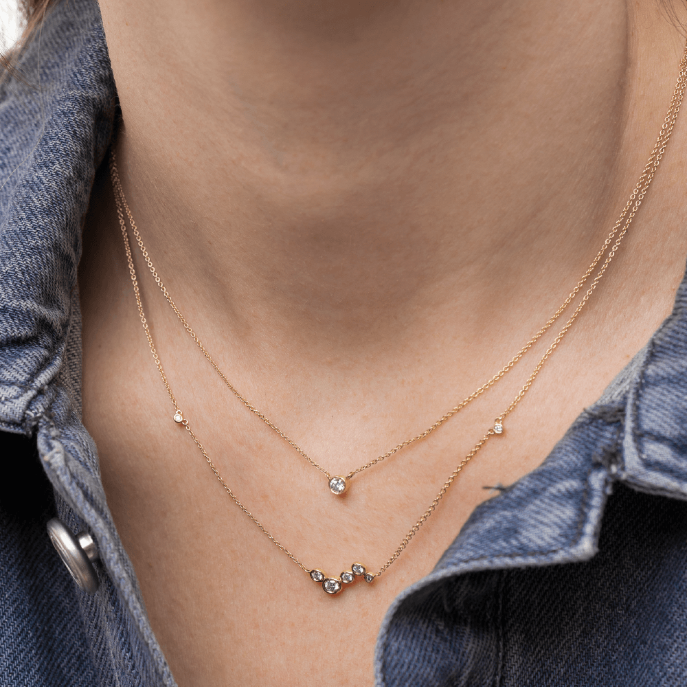 Model med to Eclipse halskæder i 14kt guld med laboratorieskabte diamanter i lag-på-lag.