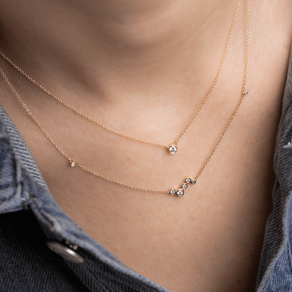 Model med to Eclipse halskæder i 14kt guld med laboratorieskabte diamanter i lag-på-lag.