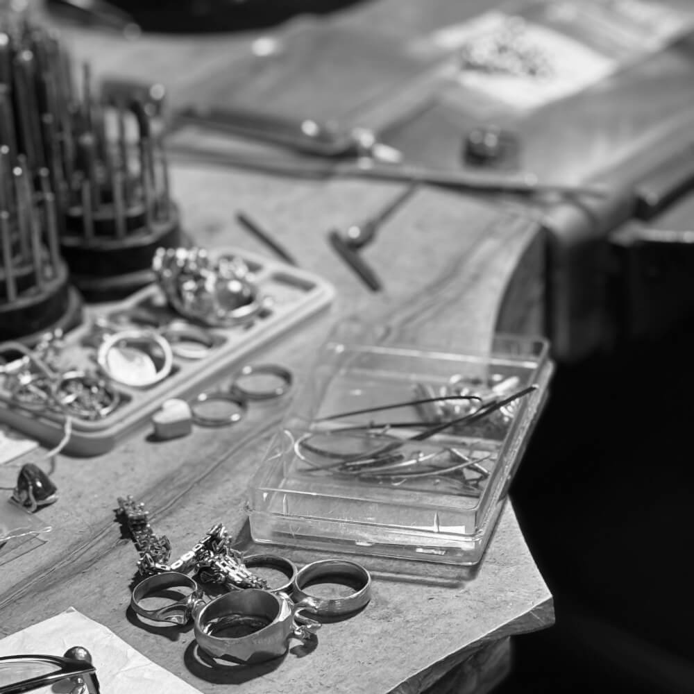 Genbrugte smykkedelkomponenter og værktøj på arbejdsbord.