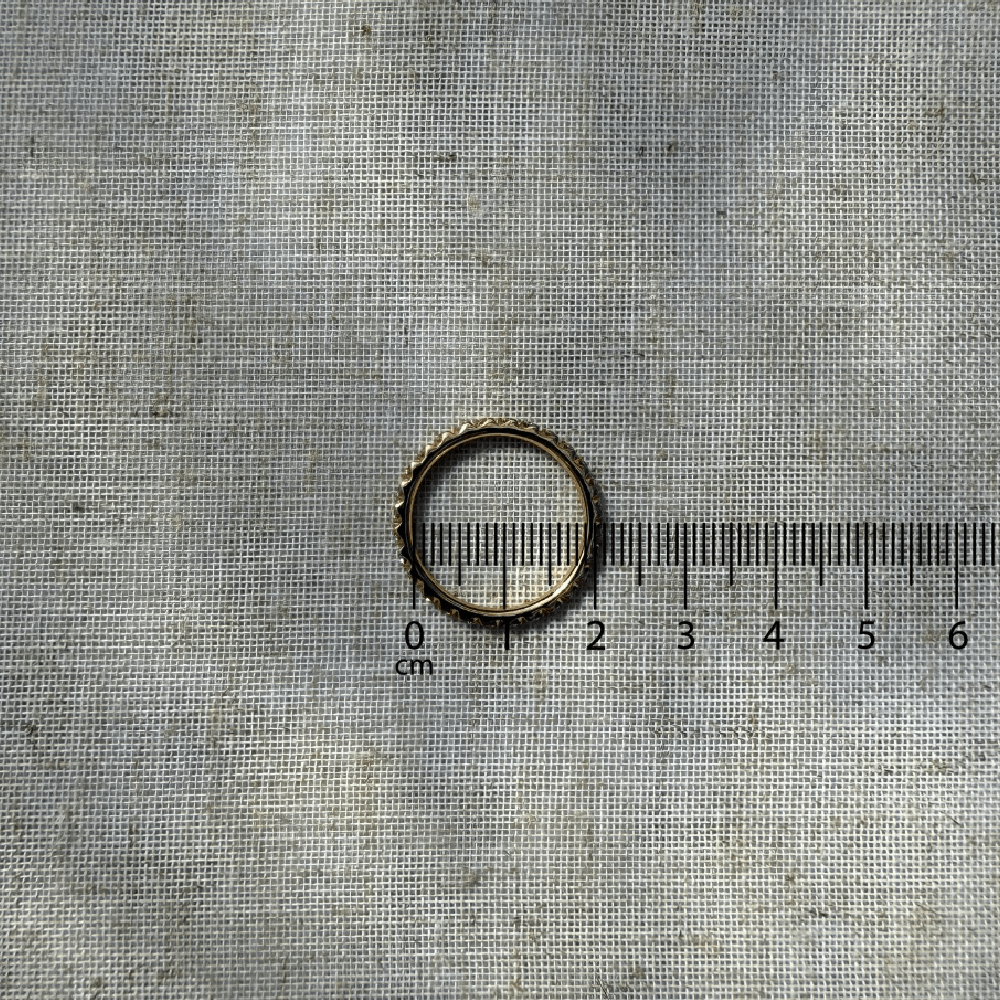 Guldring placeret på lineal for visning af størrelse i centimeter.