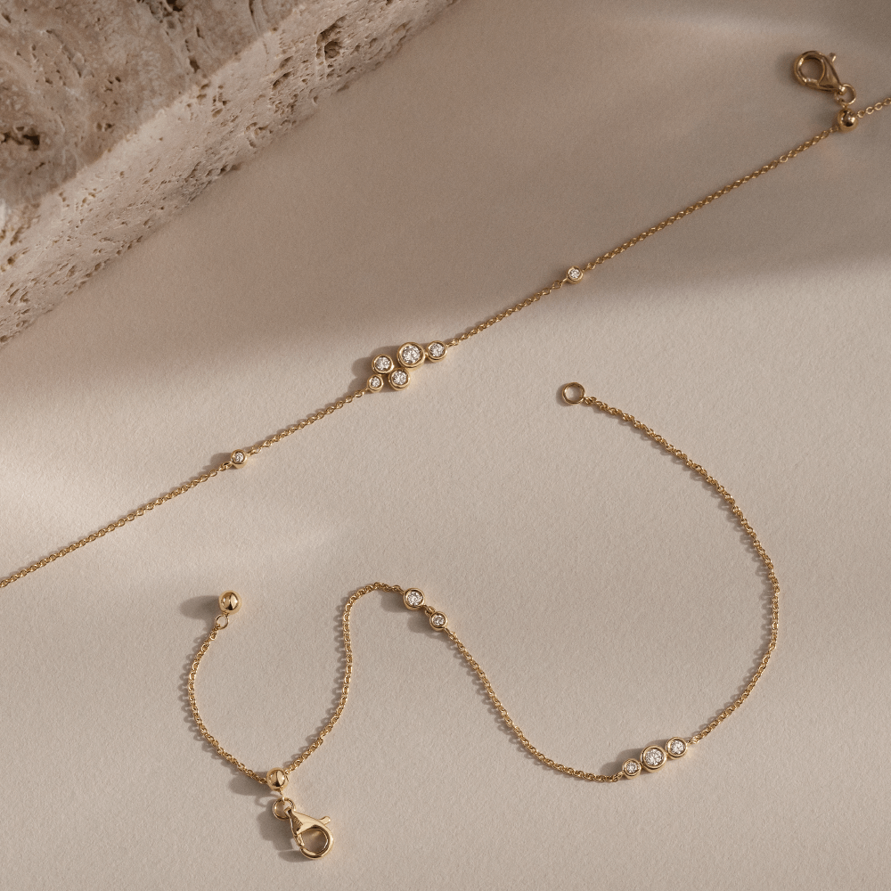 Softpack foto med Eclipse armbånd i 14 kt guld placeret ved siden af travertin sten.