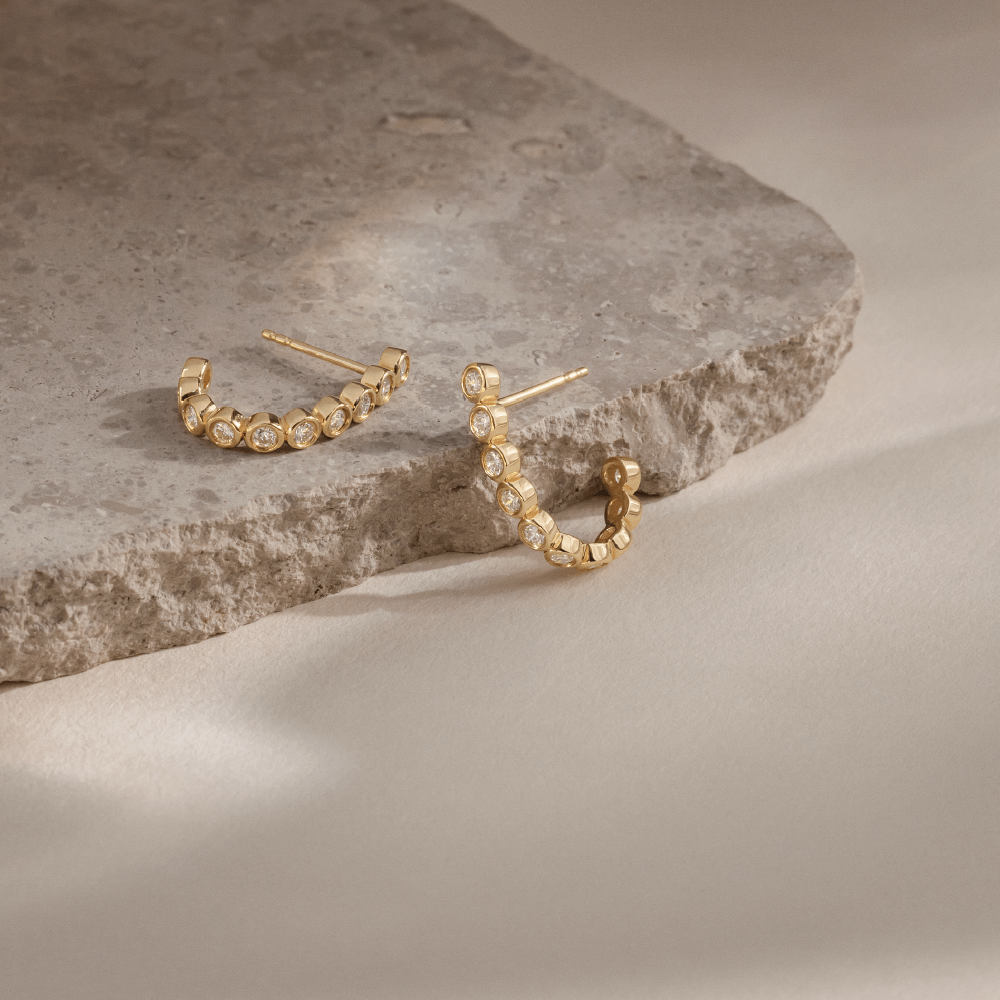 Softpack foto med Eclipse Hoops ørering i 14 kt guld placeret omkring travertin sten.