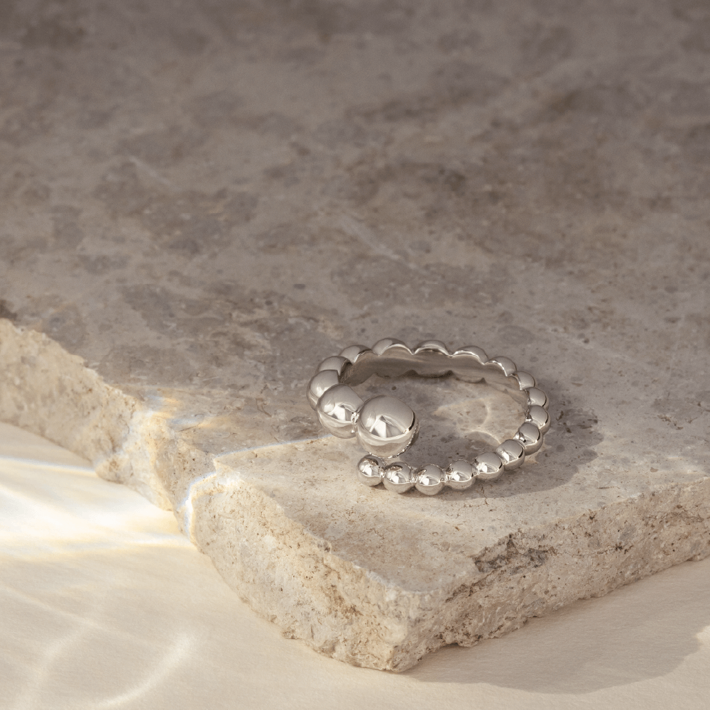 Softpack foto med en Orbis ring i sterlingsølv placeret på travertin sten.