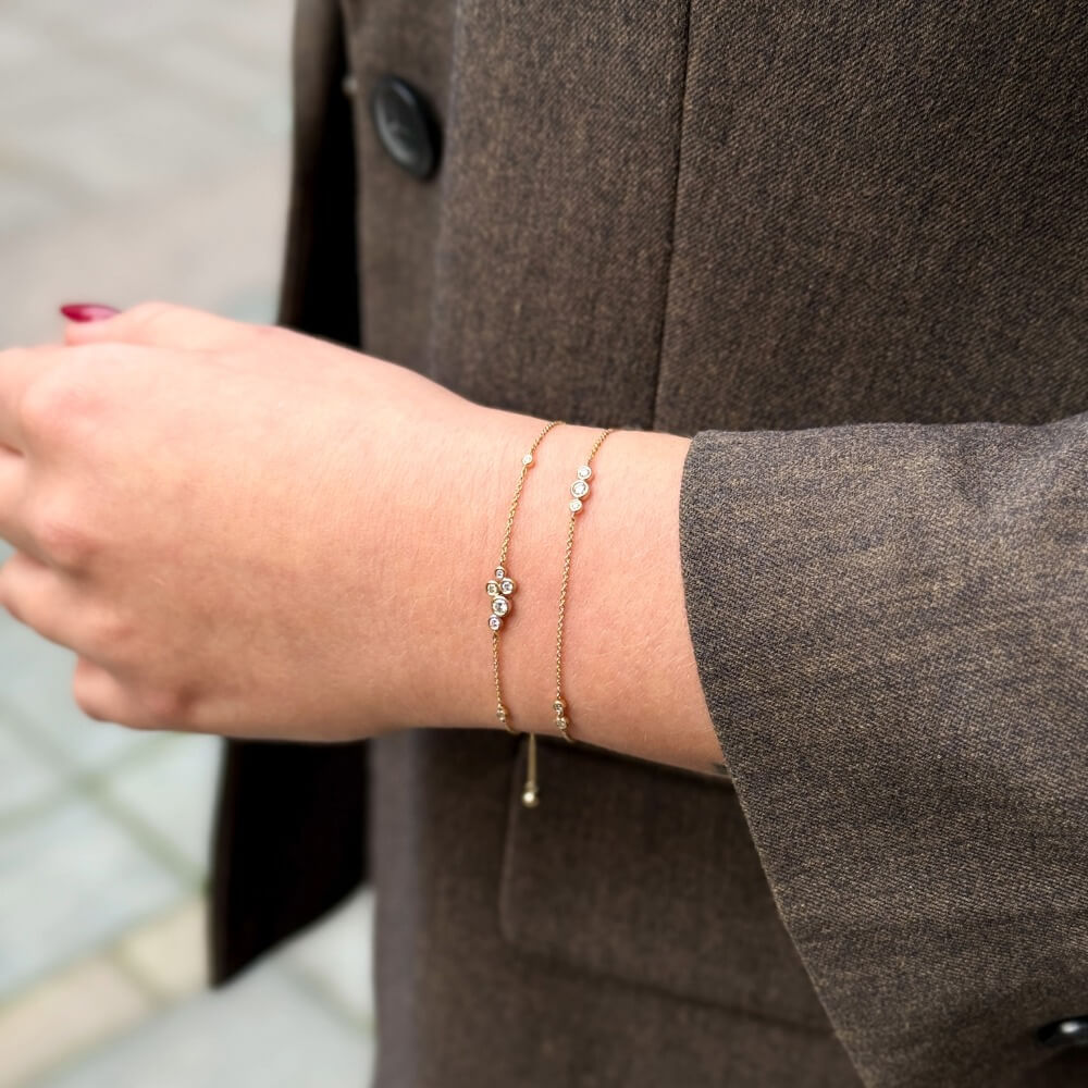 To Eclipse 14kt guldarmbånd med laboratorieskabte diamanter stylet på hånd iført brun blazer.