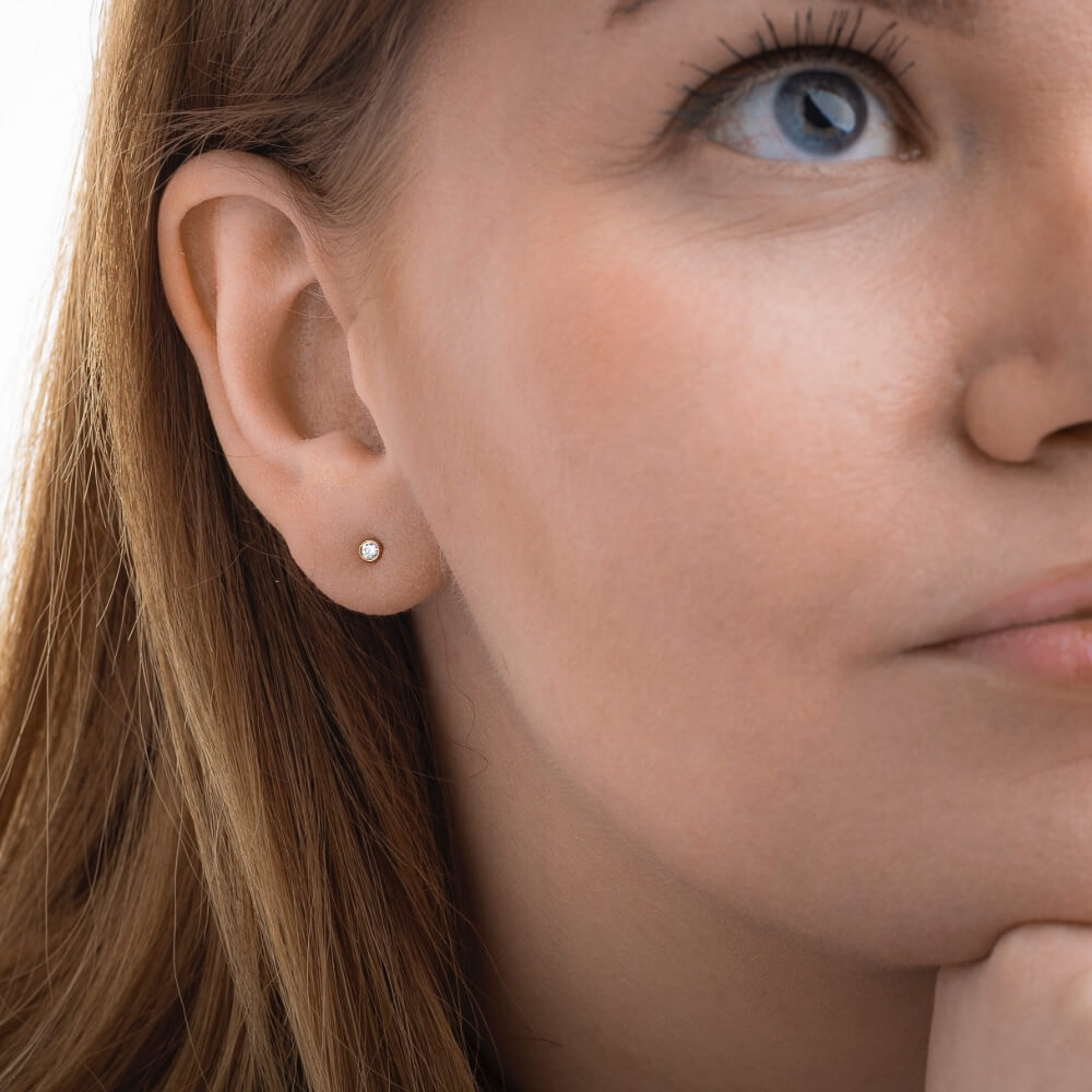 Model med Eclipse solitaire ørestik i 14 kt guld med laboratorieskabt diamant.