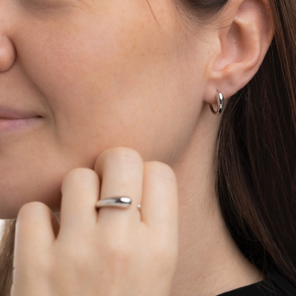 Model med Serene huggies øreringe og Serene ring i sterlingsølv.