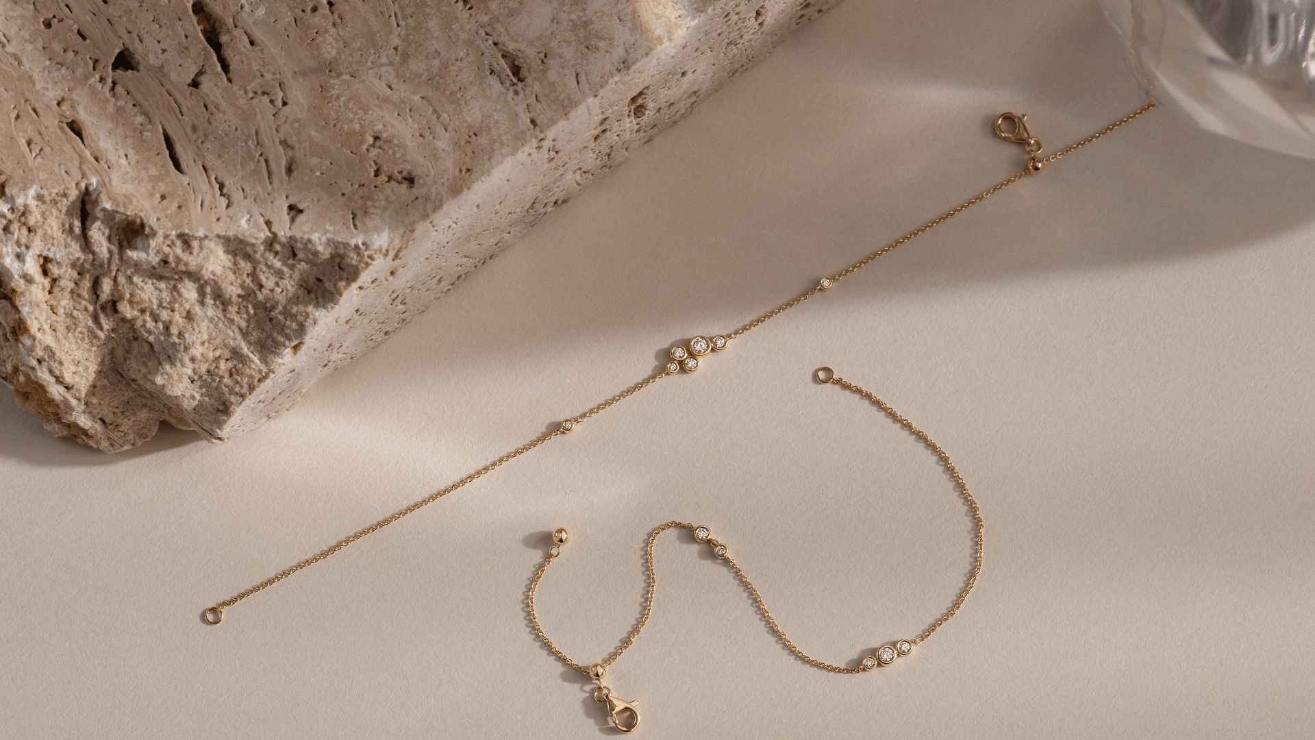 Softpack foto med Eclipse armbånd i 14 kt guld placeret ved siden af travertin sten.