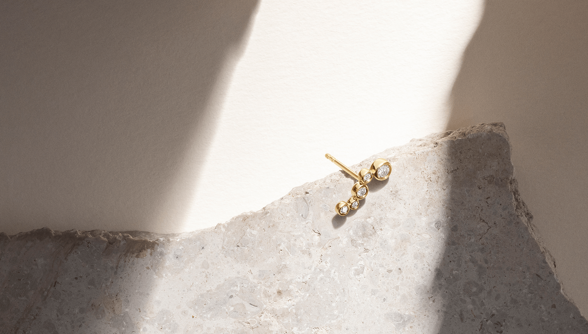 Softpack foto med Eclipse Flow øreringe i 14 kt guld på lys baggrund med lysreflektioner.