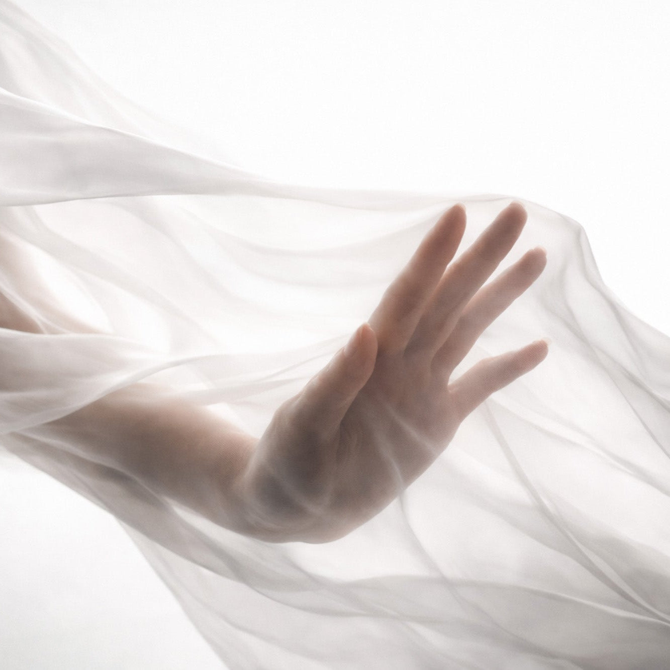 Hånd bag transparent, bølgende stof i blødt lys.