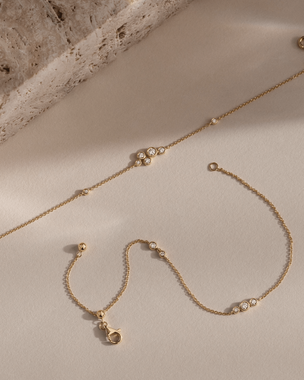 Softpack foto med Eclipse armbånd i 14 kt guld placeret ved siden af travertin sten.