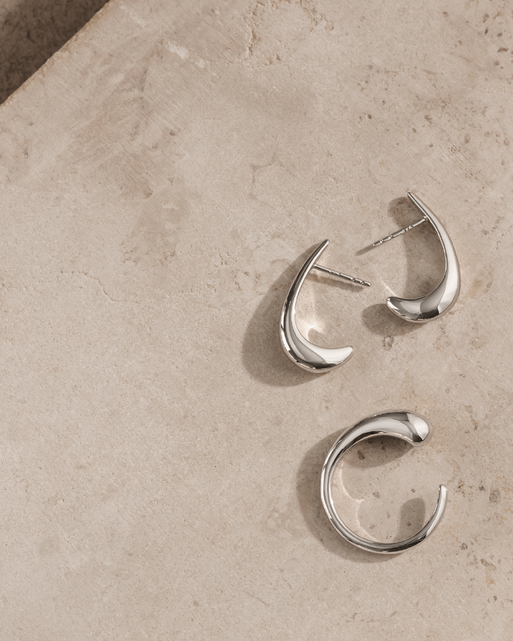 Softpack foto med Serene øreringe og Serene ring i sterlingsølv placeret på travertin sten.