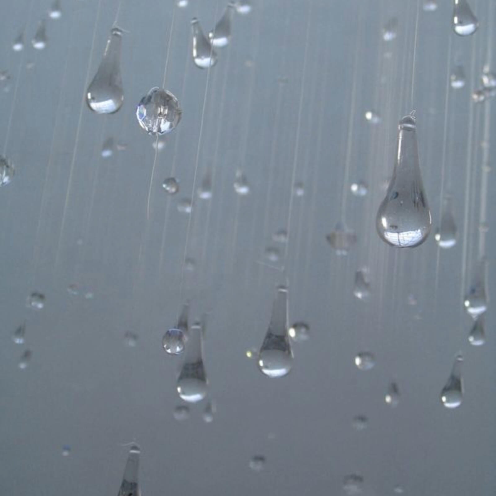 Vanddråber i bevægelse hængende i luften mod en blågrå baggrund.