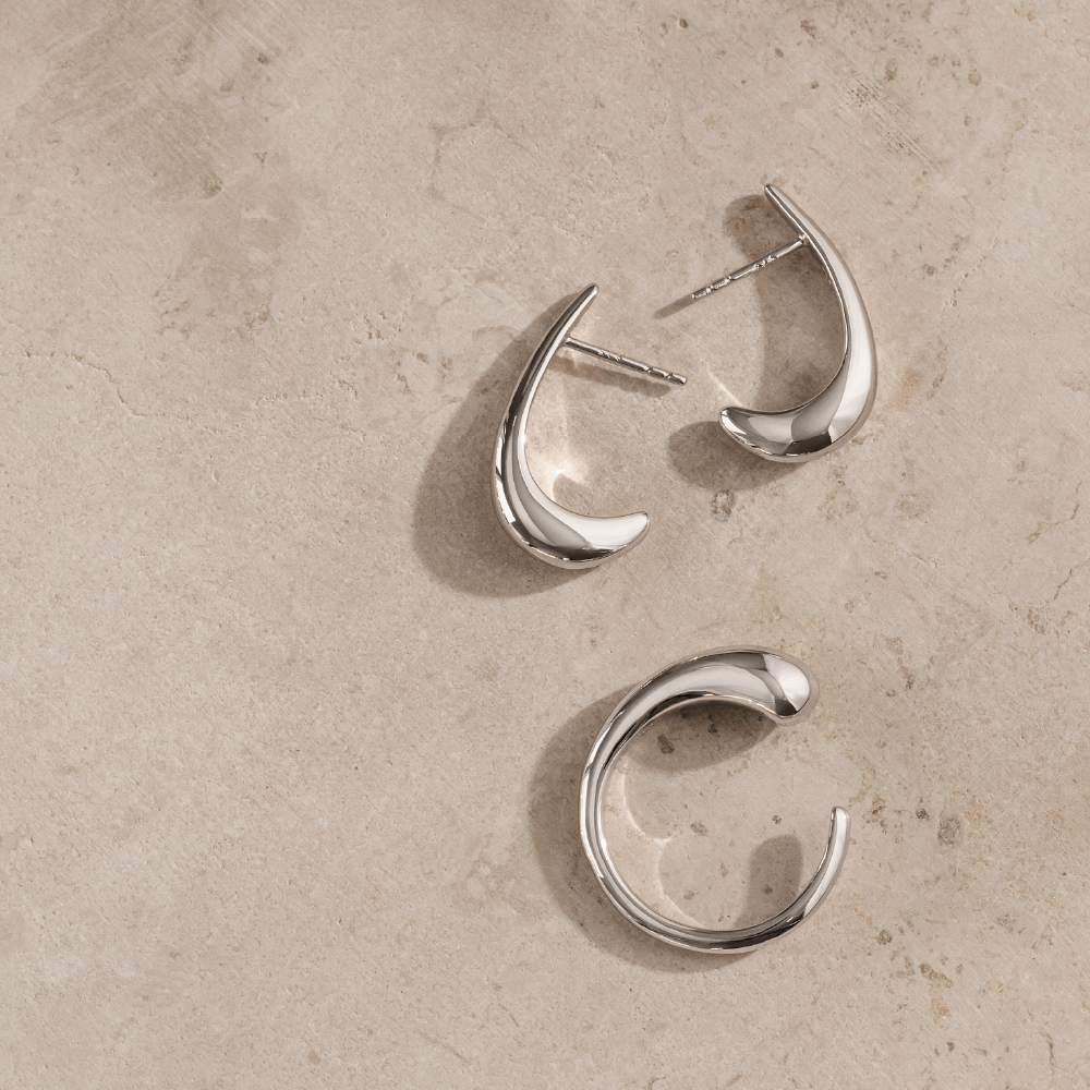 Softpack foto med Serene øreringe og Serene ring i sterlingsølv placeret på travertin sten.