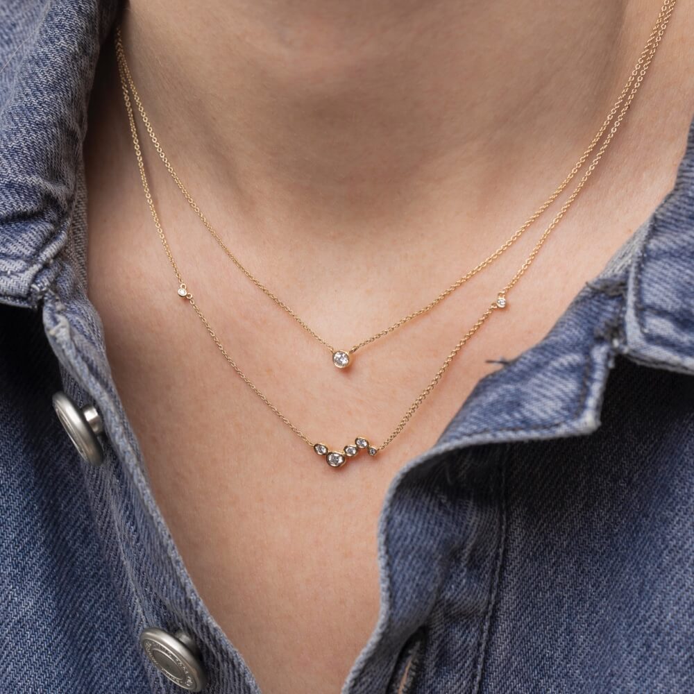 Model med to Eclipse halskæder i 14kt guld med laboratorieskabte diamanter i lag-på-lag.