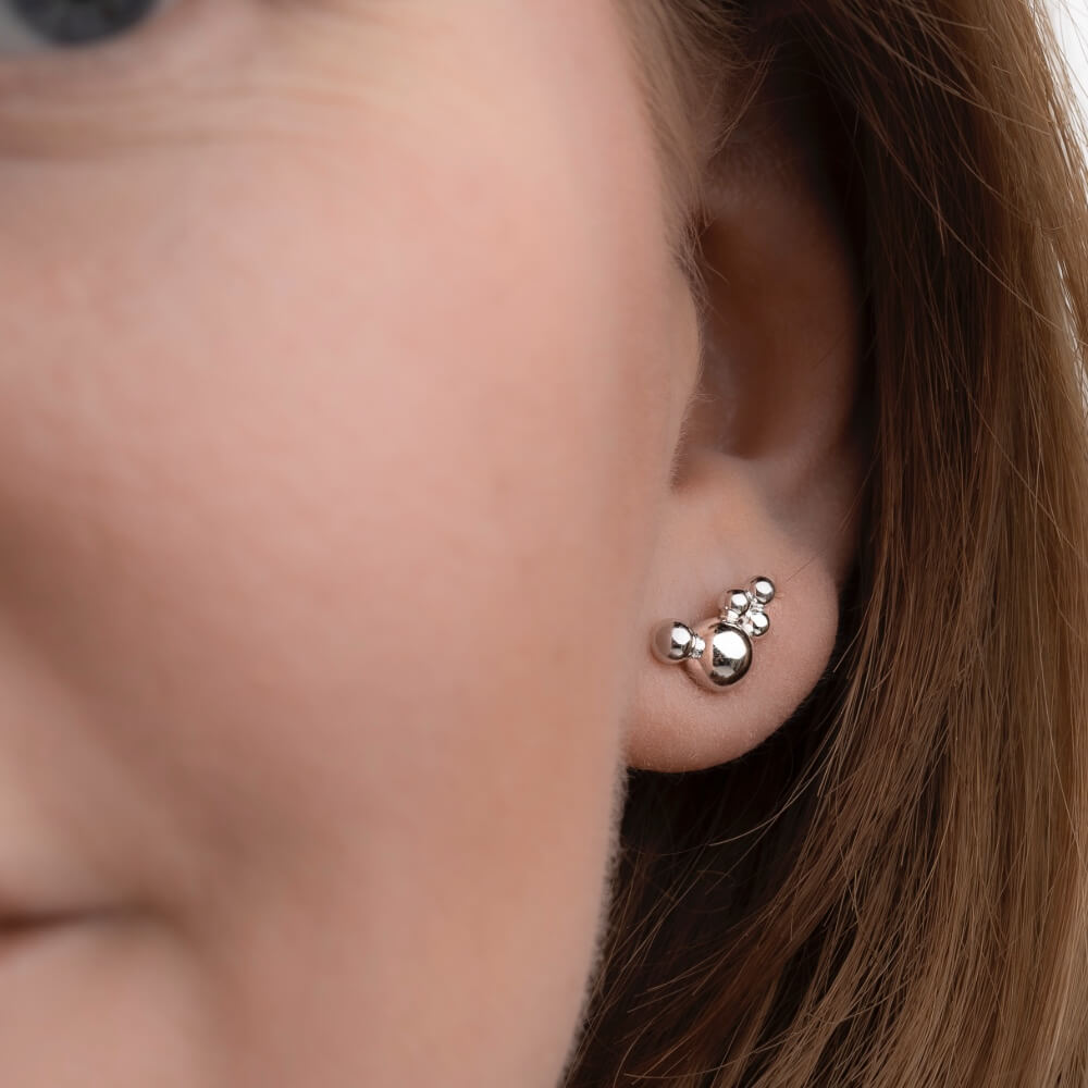 Model med Orbis Cluster ørestik i sterlingsølv med polerede kugledetaljer.