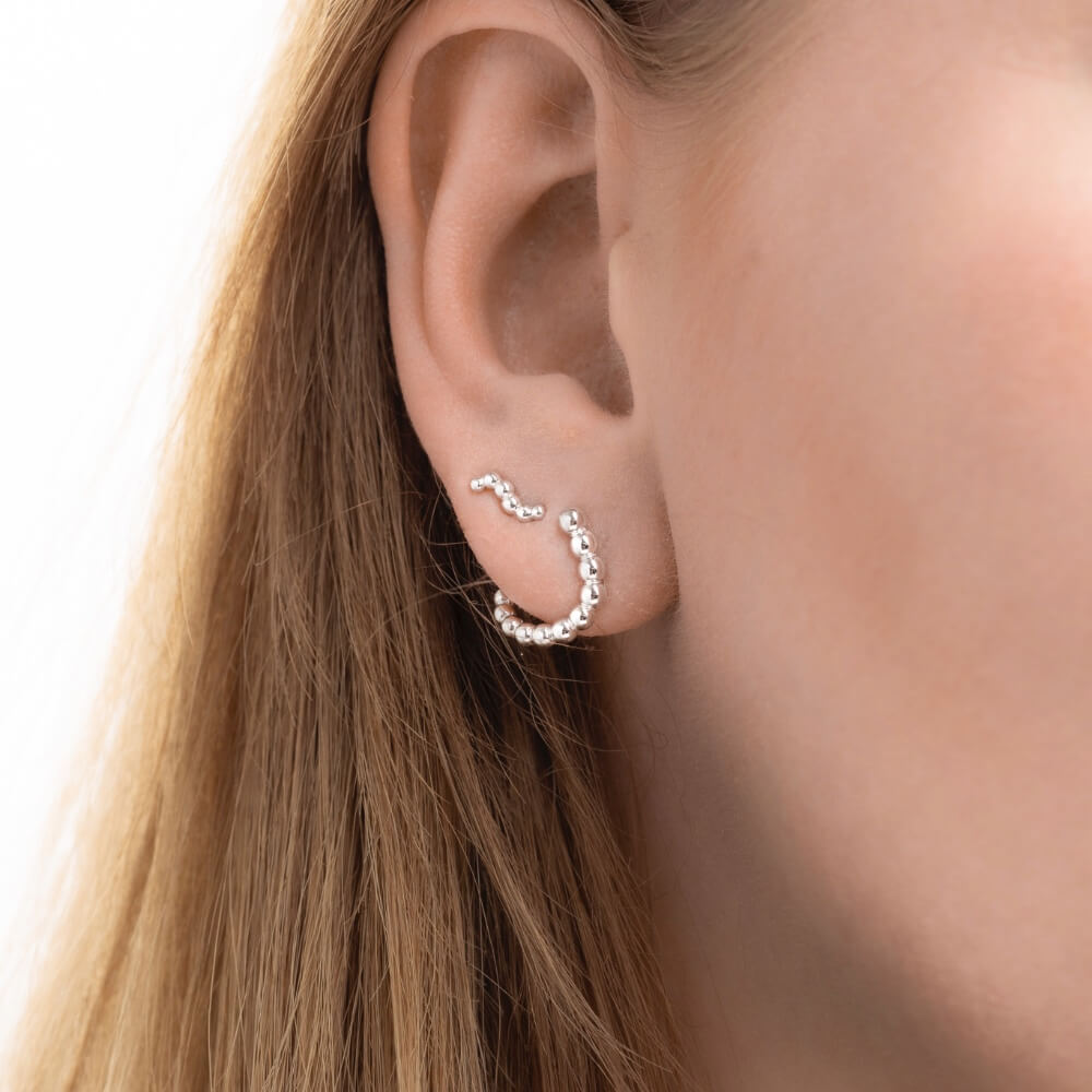 Model med Orbis Drop ørestikker og Orbis Mini ørestikker i sterlingsølv.