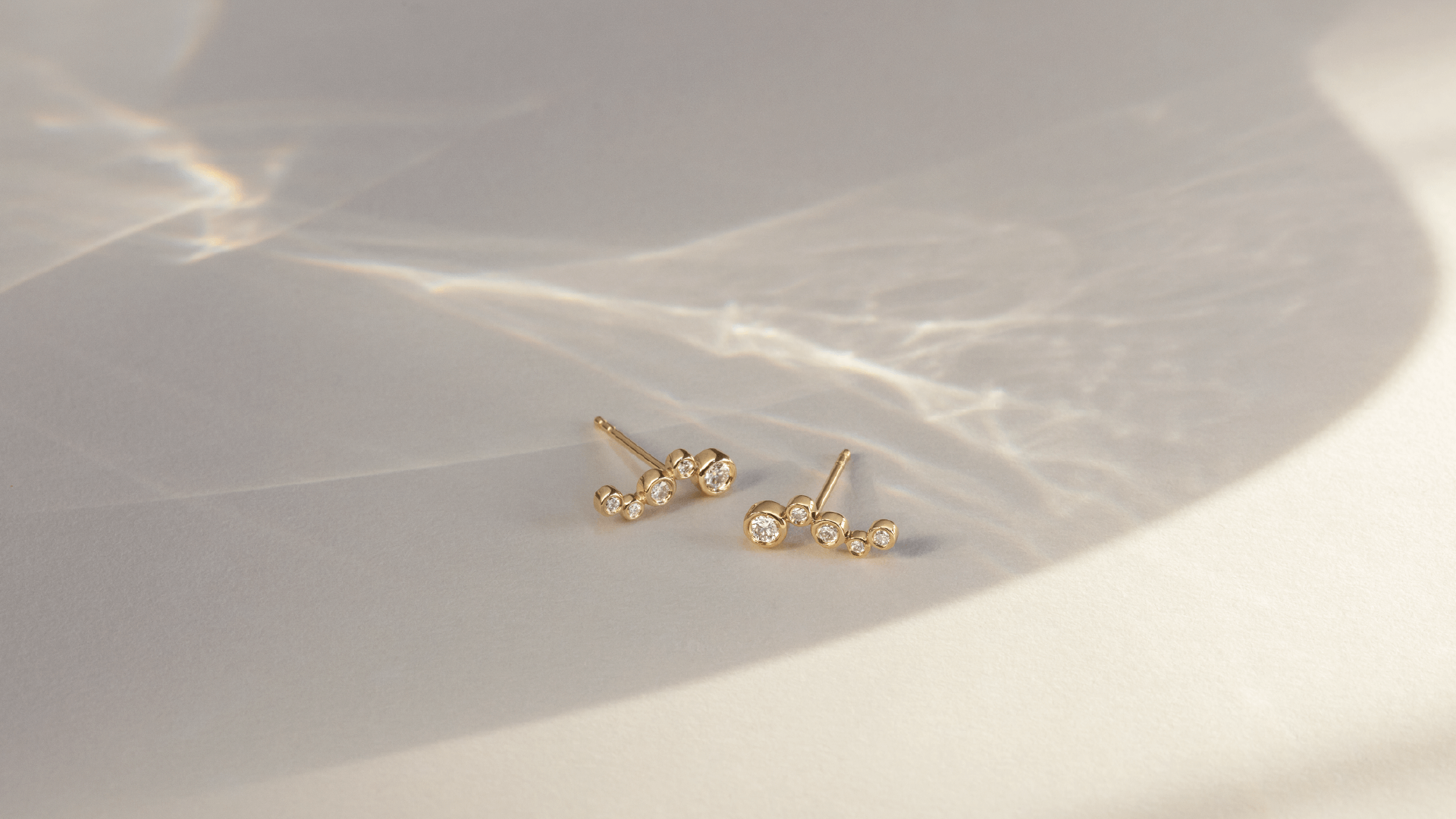 Softpack foto med Eclipse Flow øreringe i 14 kt guld på lys baggrund med lysreflektioner.